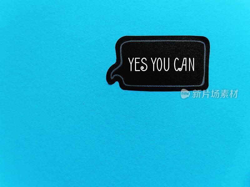 蓝色副本空间背景上的黑色贴纸，文字YES YOU CAN，自我对话或肯定的概念，以增强积极思想的力量，增加自尊和改善心态